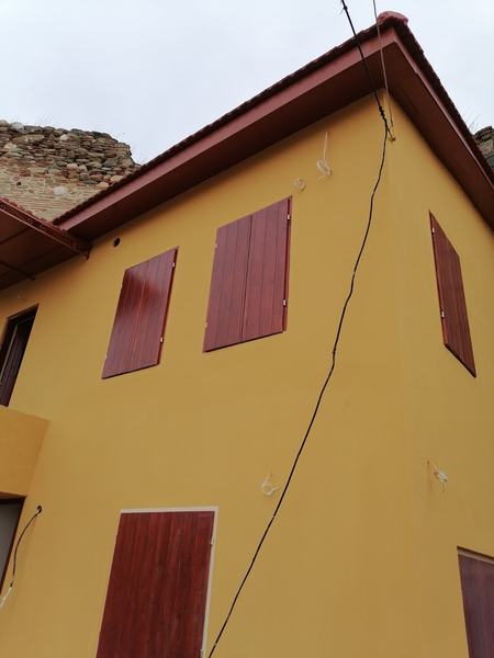 Πρόσοψη σε ώχρα με κόκκινα παντζούρια μετά την αποκατάσταση